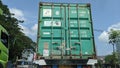 A green container is being transported by truck